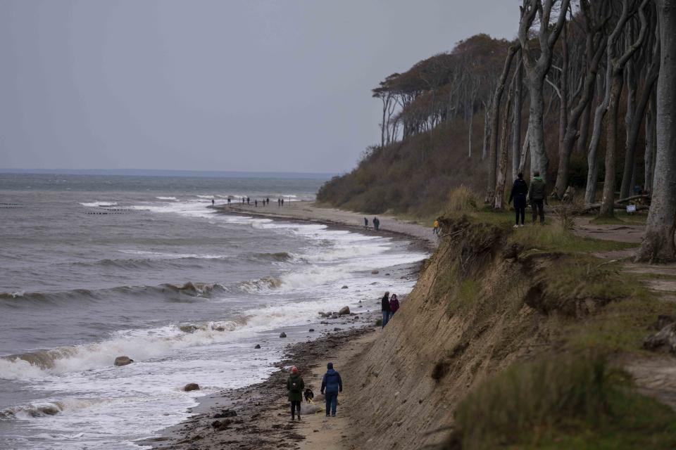 People enjoy a stormy day as the walk past the 'Gespensterwald' (Ghost forest) at the Baltic Sea in Nienhagen, Germany, Thursday, Oct. 19, 2023. (AP Photo/Matthias Schrader)