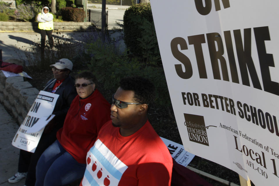 FILE - In this Sept. 18, 2012 file photo, teachers picket outside Morgan Park High School in Chicago. A threatened strike in 2019 by Chicago teachers would carry on the city's historically significant role in education labor disputes, including the 2012 strike cited by teachers around the country as inspiration for walkouts and other protests in recent years. That seven-day strike was a dramatic test of the Chicago Teachers Union's effort to force expanded negotiations into social issues beyond the typical give-and-take over pay and benefits (AP Photo/M. Spencer Green File)