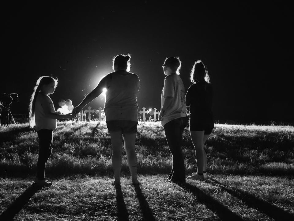 <p>A famlly stands near 26 crosses set up in a baseball field a few blocks from the site of Sunday’s shooting during a memorial service on Monday nigth in Sutherland Springs, Texas. (Photo: Holly Bailey/Yahoo News) </p>