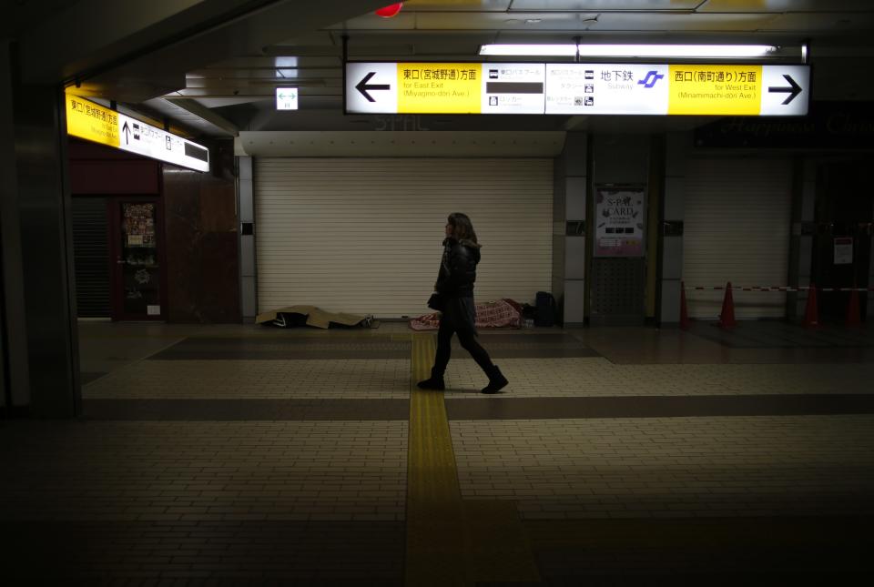 Shizuya Nishiyama, a 57-year-old homeless man from Hokkaido, and an another homeless man sleep as a passerby walks past at Sendai Station in Sendai, northern Japan