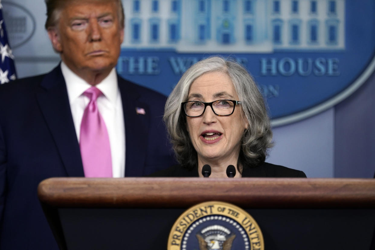 Dr. Anne Schuchat speaks at a podium with then-President Donald Trump behind her