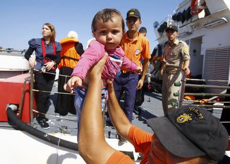 A member of the Turkish coast guards carries a baby of Syrian migrant on the shore in Cesme, near the Aegean port city of Izmir, Turkey, August 11, 2015. REUTERS/Osman Orsal