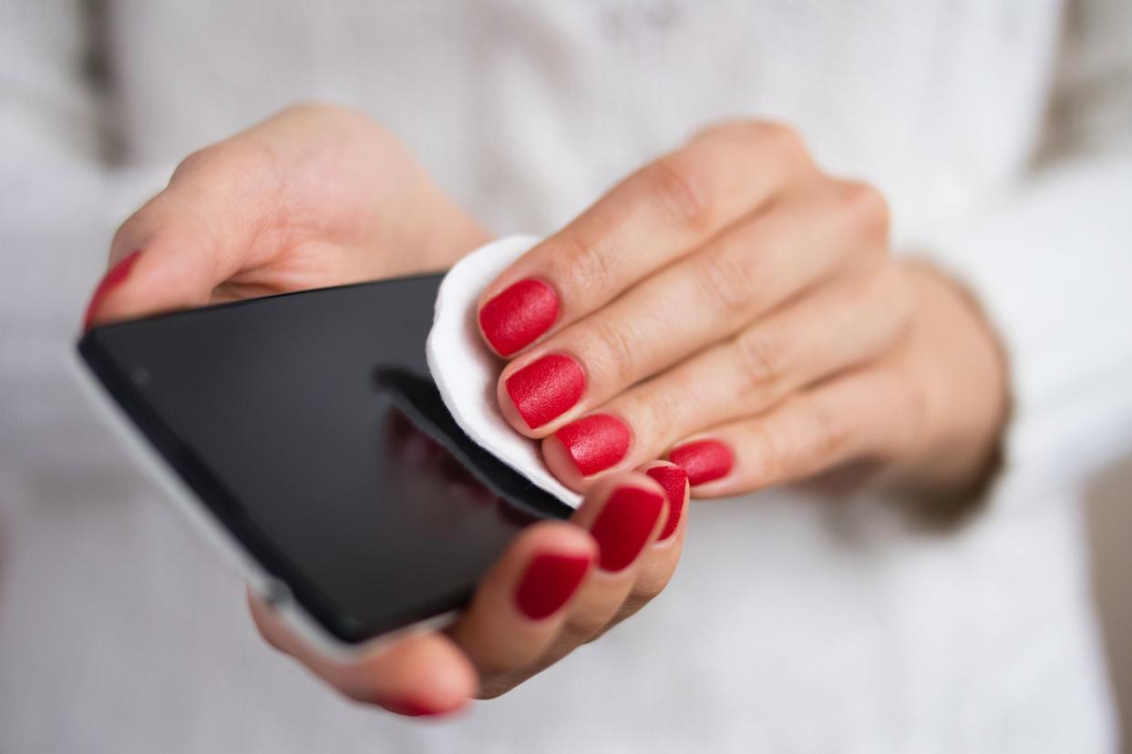 woman cleaning cellphone with wipe