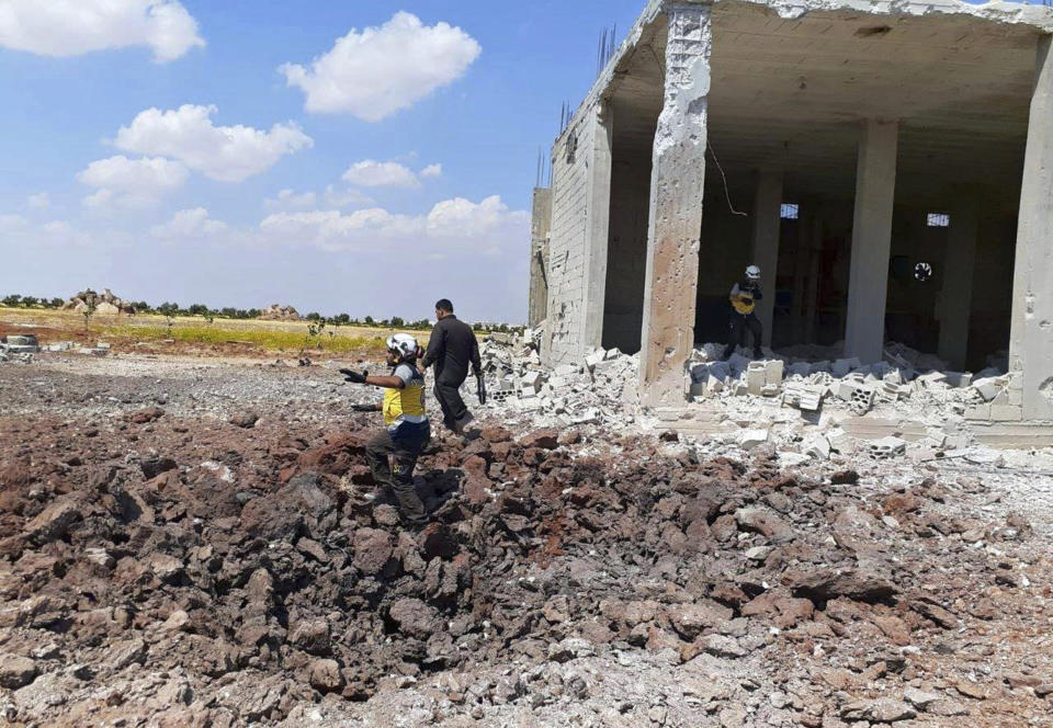 This photo provided by the Syrian Civil Defense White Helmets, shows a Civil Defense worker searching for victims from under the rubble of a destroyed building that was hit by airstrikes in the northern town of Maaret al-Numan, in Idlib province, Syria, Thursday, Aug. 22, 2019. Syrian warplanes carried out airstrikes on towns and villages north of Khan Sheikhoun, including the town of Maaret al-Numan, according to opposition activists. Maaret al-Numan, like Khan Sheikhoun sits on the highway linking Damascus with the northern city of Aleppo, Syria's largest. (Syrian Civil Defense White Helmets via AP)