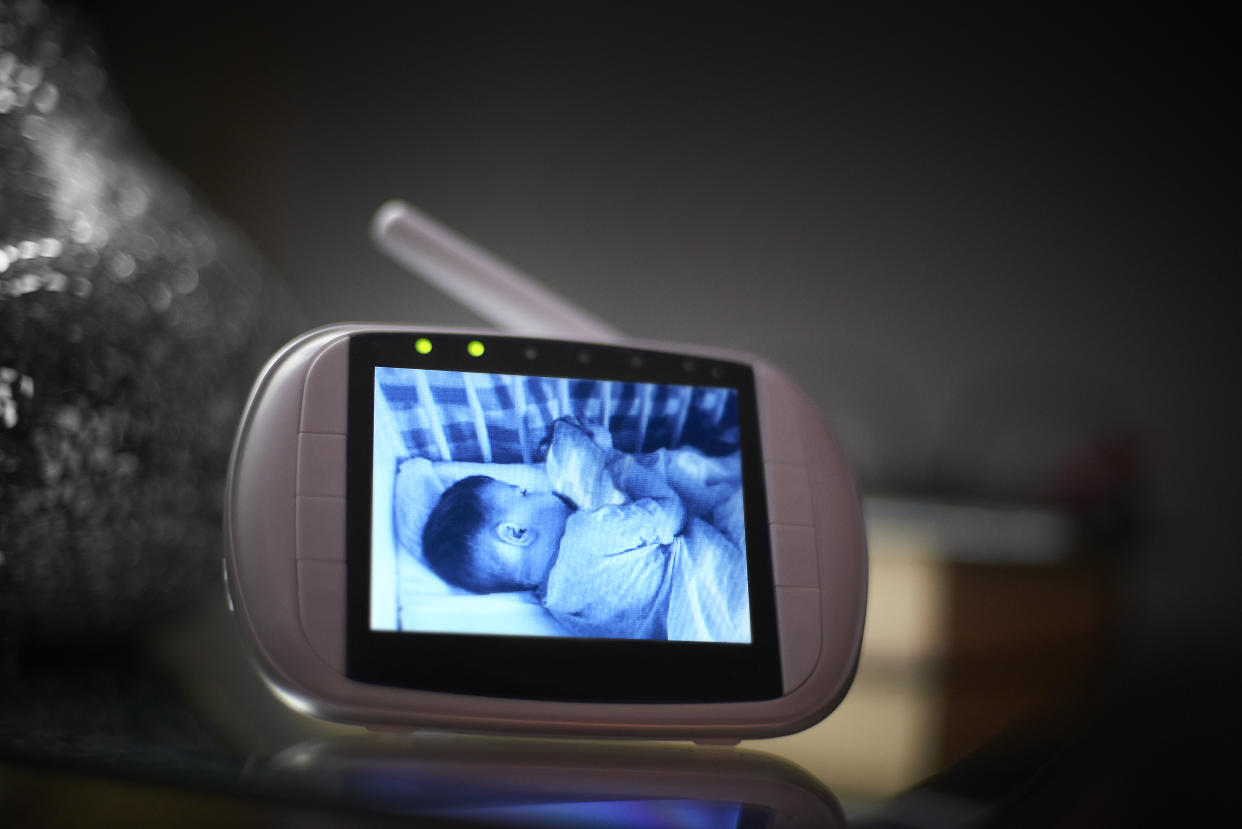 Baby monitor on bedside table in the bedroom with the image of the baby sleeping on the screen