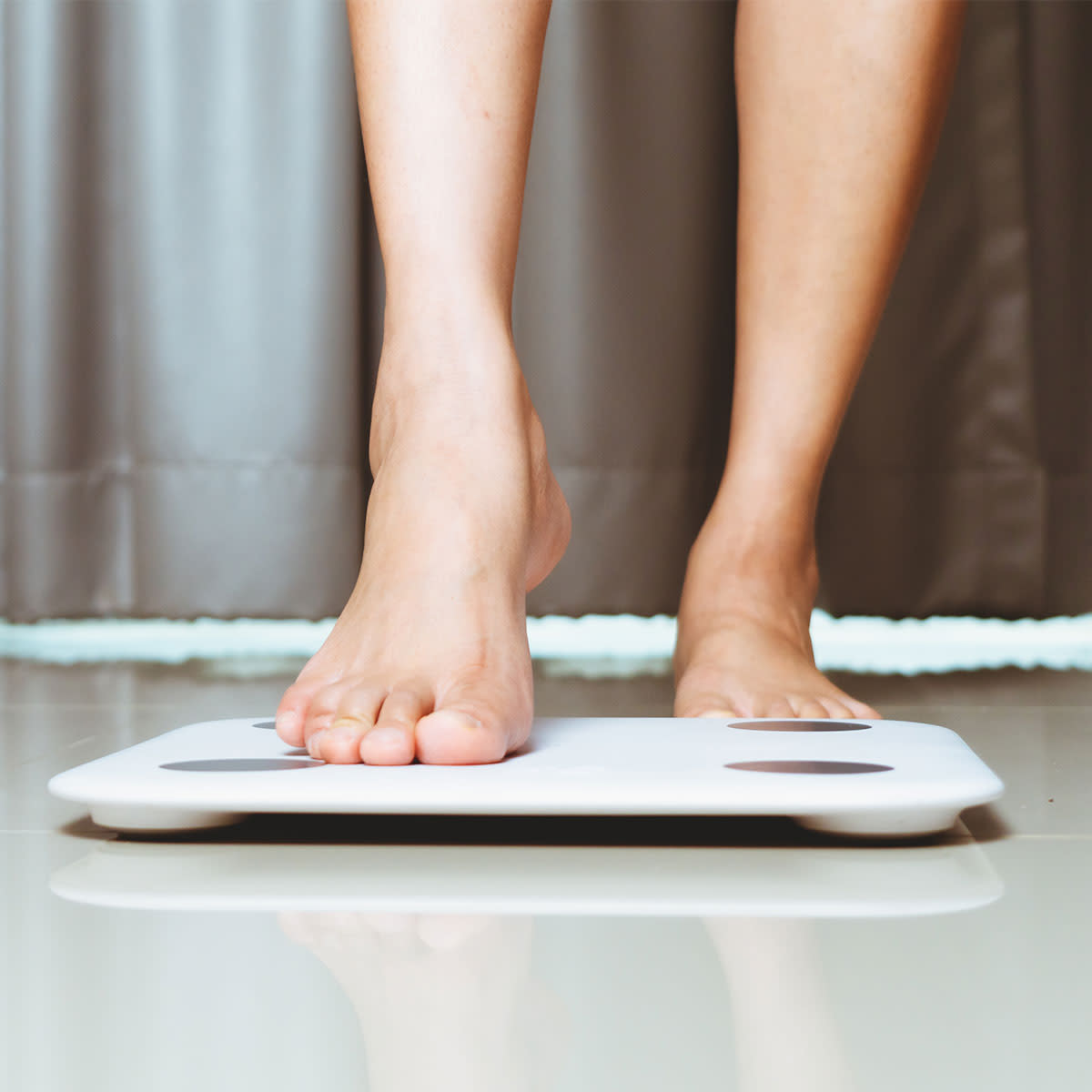 woman gently stepping onto a scale