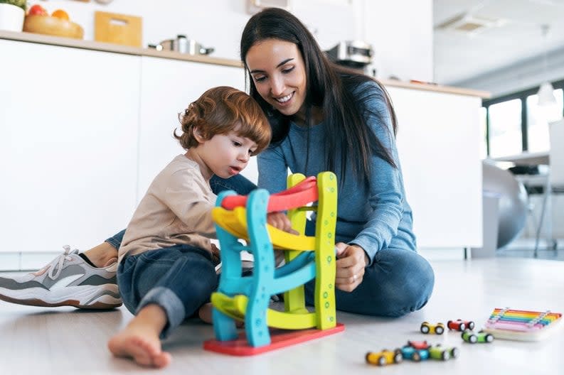 Mother and young son play with car toys together.