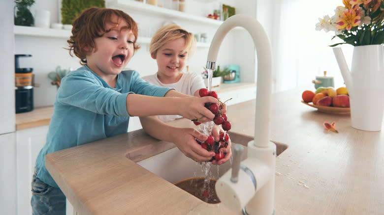 kids washing cherries at sink