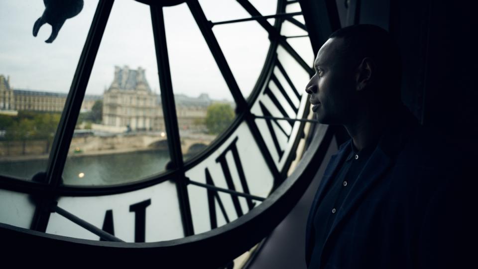 A photo of a man standing inside London's Big Ben and looking out at the city in Netflix show Lupin