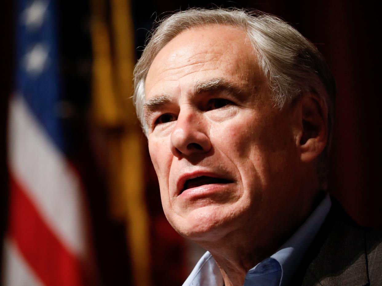 Texas Governor Greg Abbott stares with an American flag in the background.