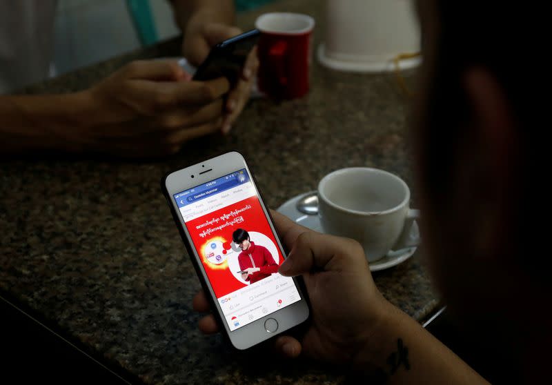 FILE PHOTO: A cellphone user looks at a Facebook page at a shop in Latha street in Yangon