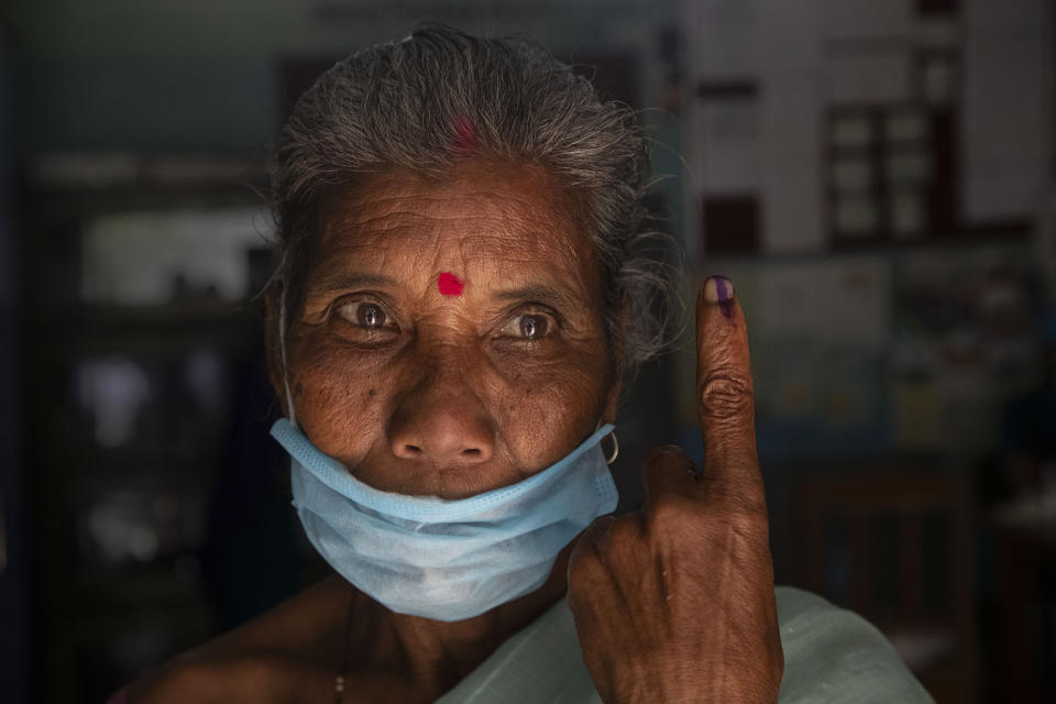 An elderly tribal Mishing displays the indelible ink on her finger after casting her vote at a polling center during the first phase of Assam state elections in Majuli, India, Saturday, March 27, 2021. Voting began Saturday in two key Indian states with sizeable minority Muslim populations posing a tough test for Prime Minister Narendra Modi’s popularity amid a months-long farmers’ protest and the economy plunging with millions of people losing jobs because of the coronavirus pandemic. (AP Photo/Anupam Nath)