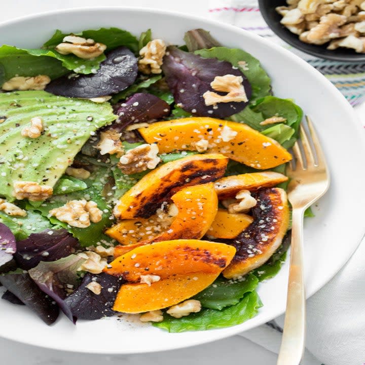 Salad on a white dish with pecans and squash slices