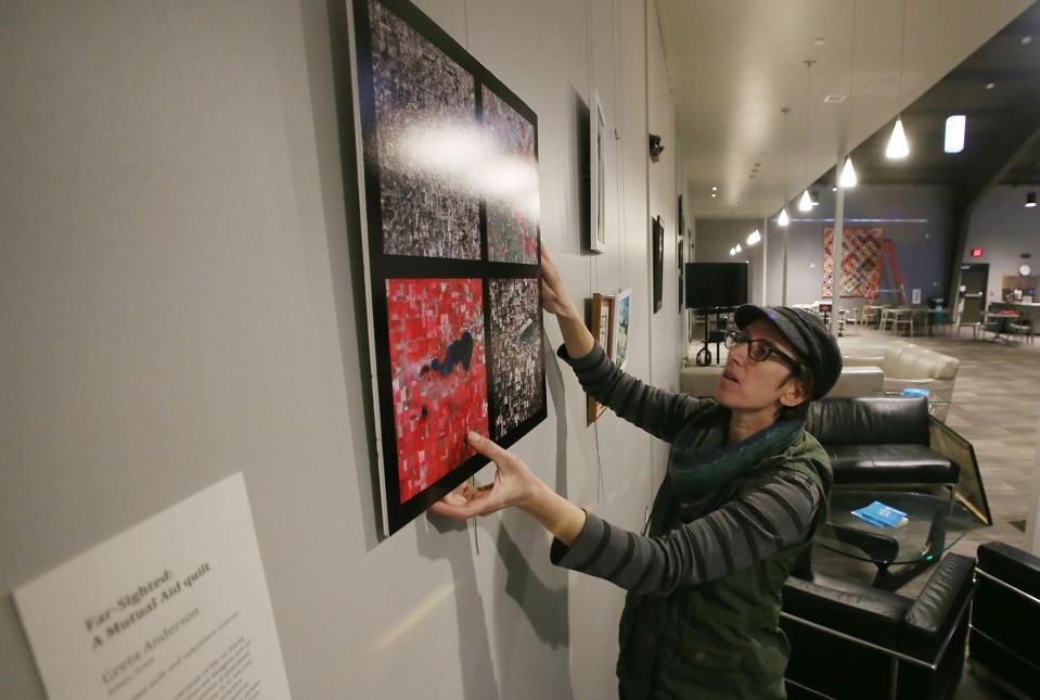 Alice McGary, artist and volunteer at Mustard Seed Community Farm, installs photos and quilts for an upcoming art show at Harvest Vineyard Church of Ames. A free public reception to kick off the community art show will be held Saturday from 6 p.m. to 8 p.m.