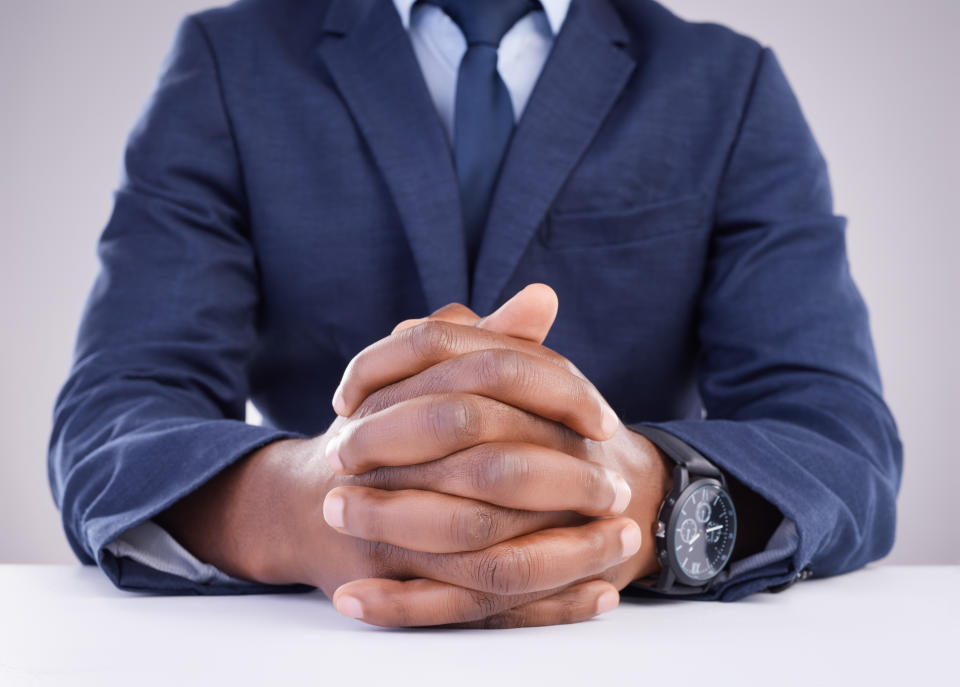 Man, hand and angry hr in meeting for compliance, complaint or discipline against a wall background. Hands, together and boss waiting for bad behavior discussion in the workplace, bullying or fired