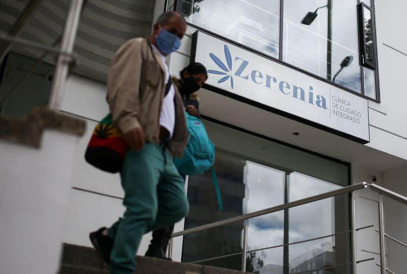 People wearing face masks walk in front of the Zerenia clinic, the first clinic specializing in medical marijuana treatments, in Bogota