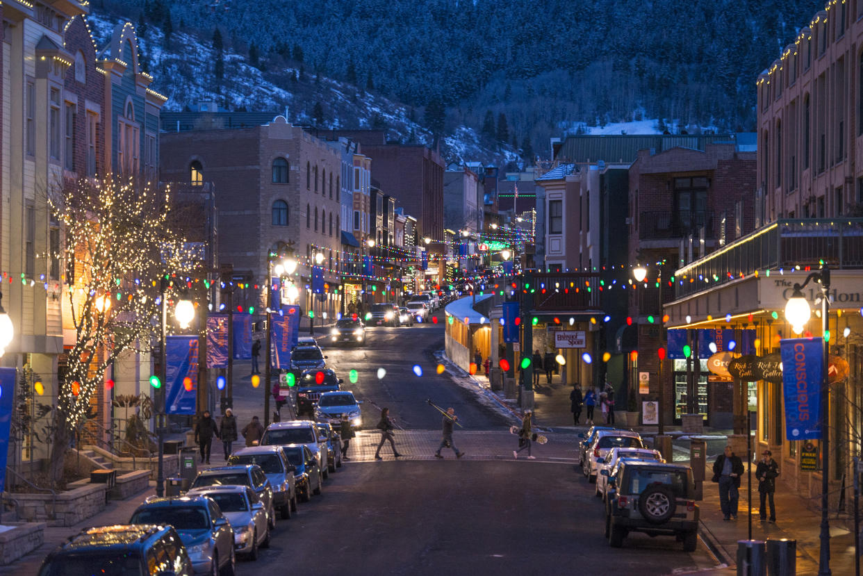  A family carrying skis walks across Main Street in Park City, Utah, at night. 