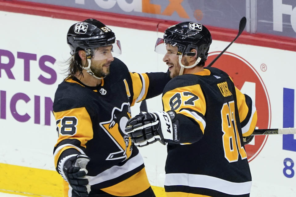 FILE - In this March 15, 2021, file photo, Pittsburgh Penguins' Sidney Crosby (87) celebrates with Kris Letang (58) after scoring against the Boston Bruins during the first period of an NHL hockey game in Pittsburgh. The Penguins and Islanders meet in Game 1 of their opening-round series on Sunday. The Islanders swept Pittsburgh in the first round of the playoffs in 2019. (AP Photo/Keith Srakocic)