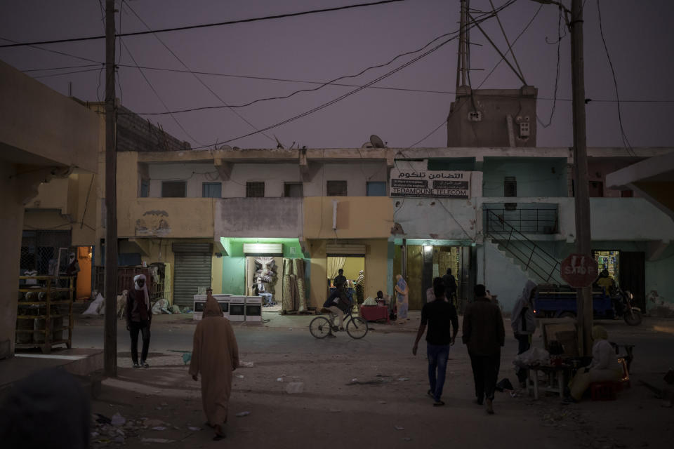 Varias personas caminan al atardecer por las calles de Nuadibú, Mauritania, el 30 de noviembre de 2021. (AP Foto/Felipe Dana)