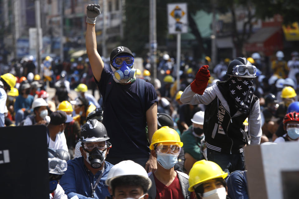 Protesters take positions behind a makeshift barricade as armed riot policemen gather in Yangon, Myanmar, Monday, March 8, 2021. Myanmar security forces continued to clamp down on anti-coup protesters, firing tear gas to break up a crowd of around 1,000 people who were demonstrating in the capital, Naypyitaw. The protesters deployed fire extinguishers to create a smoke screen as they fled from authorities. (AP Photo)