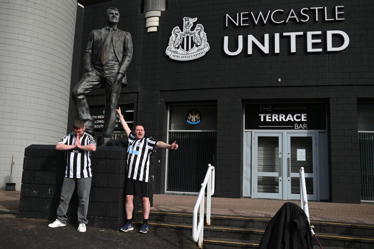 A Newcastle United supporters pose with the statue of late former manager Bobby Robson outside the club's stadium at St James' Park in Newcastle upon Tyne in northeast England on October 8, 2021, after the sale of the football club to a Saudi-led consortium was confirmed the previous day. - A Saudi-led consortium completed its takeover of Premier League club Newcastle United on October 7 despite warnings from Amnesty International that the deal represented 