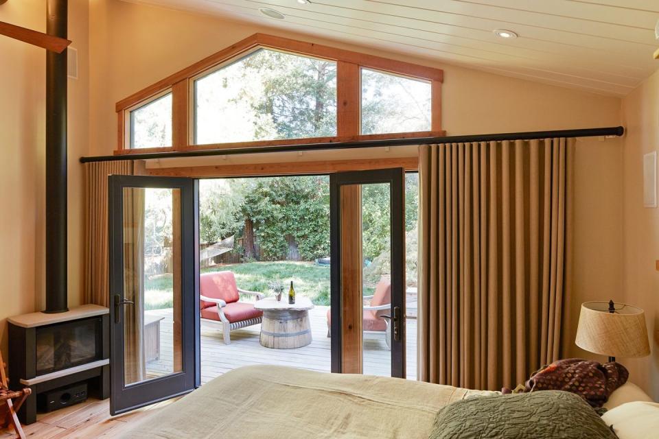 <p>This rustic bedroom in Silicon Valley brings the outdoors in with a set of large glass doors. Cozy fabrics complete the light-filled interior. Design by <a href="https://deringhall.com/interior-designers/staprans-design" rel="nofollow noopener" target="_blank" data-ylk="slk:Staprans Design;elm:context_link;itc:0;sec:content-canvas" class="link ">Staprans Design</a>.</p>