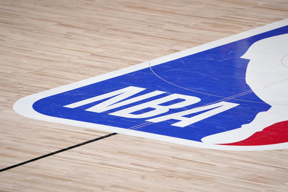 FILE - In this Sept. 2, 2020, file photo, the NBA logo is displayed at center court during an NBA first-round playoff basketball game between the Houston Rockets and Oklahoma City Thunder in Lake Buena Vista, Fla. NBA training camps open around the league Tuesday, Dec. 1, 2020,though on-court sessions will be limited to individual workouts and only for those players who have gotten three negative coronavirus test results back in the last few days. (AP Photo/Mark J. Terrill, File)