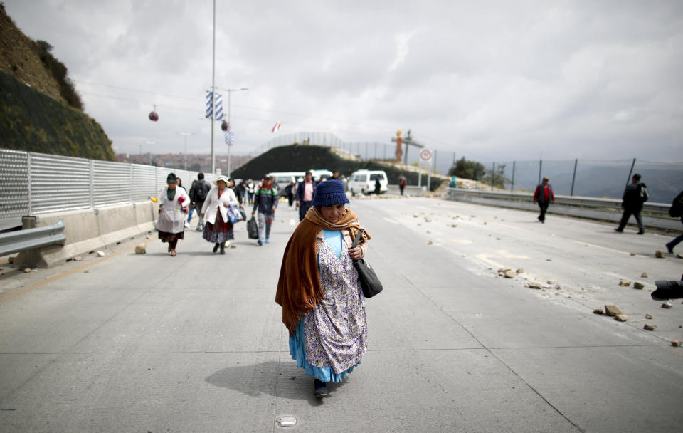 Pedestrians walk alongside a highway that has been blocked by supporters of former President Evo Morales, in El Alto, Bolivia, Thursday, Nov. 14, 2019. In self-exile in Mexico after resigning under pressure from the armed forces, Morales says he would be willing to return to Bolivia, and his supporters are making a show of force in the streets while his party controls a majority in both houses of Congress. (AP Photo/Natacha Pisarenko)