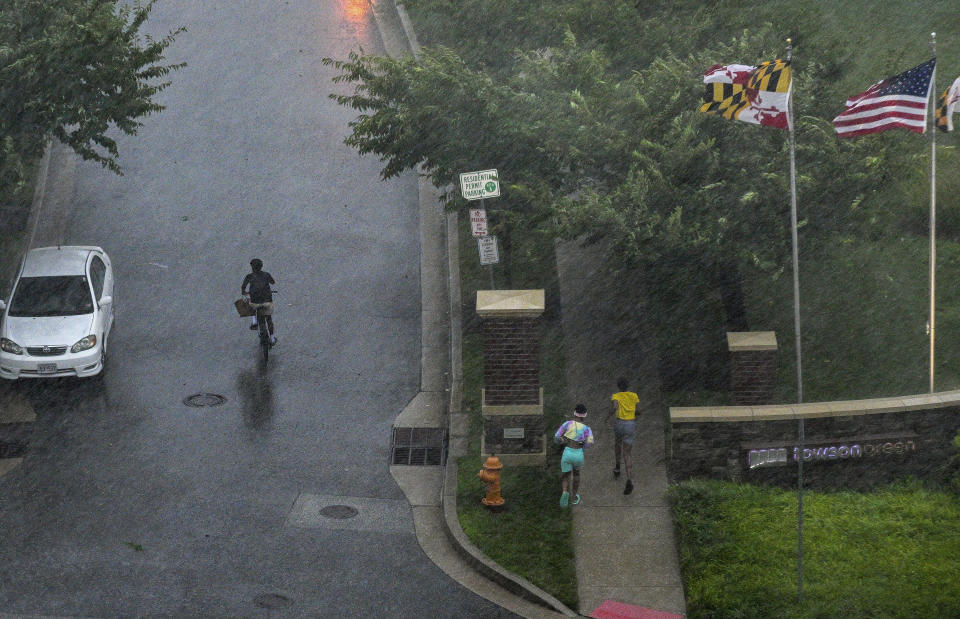 People sprint for shelter as a line of thunderstorms hit downtown Towson, Md., Monday, Aug. 7, 2023. (Jerry Jackson/The Baltimore Sun via AP)