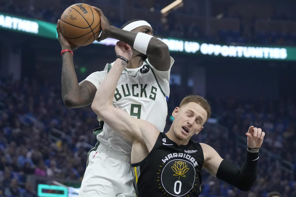 Milwaukee Bucks forward Bobby Portis Jr., top, grabs a rebound over Golden State Warriors guard Donte DiVincenzo (0) during the first half of an NBA basketball game in San Francisco, Saturday, March 11, 2023. (AP Photo/Jeff Chiu)