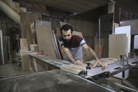 Ali Hedieloo cuts a piece of wood at his furniture workshop in the southern suburbs of Tehran, Iran, Friday, July 30, 2021. New legislation proposed by Iran's hard-line lawmakers that is designed to restrict access to social media applications in Iran has sent a wave of panic through society, stirring concerns among young Iranians, social media users and business owners. Like an estimated 1 million other Iranians, Hedieloo uses social media to find customers. (AP Photo/Vahid Salemi)