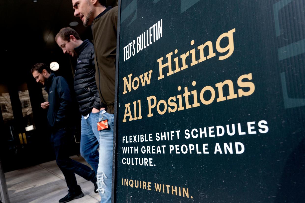 Pedestrians walk past a Now Hiring sign in Arlington, Virginia, on March 16, 2022. - The US unemployment rate has fallen to below four percent, but many companies have continued to report challenges finding staff. Some 11.3 million jobs remained open in January, according to Labor Department figures. (Photo by Stefani Reynolds / AFP) (Photo by STEFANI REYNOLDS/AFP via Getty Images)