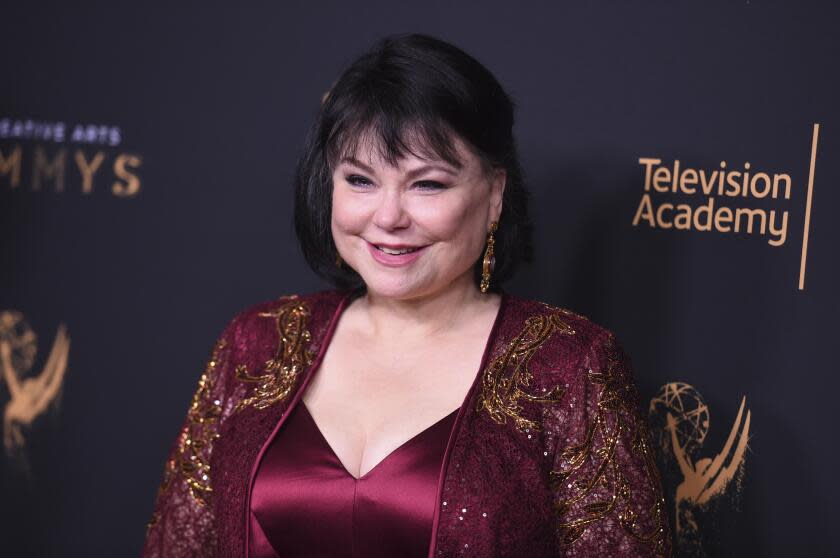 Delta Burke smiles and poses in a burgundy and gold set at the Creative Arts Emmy Awards