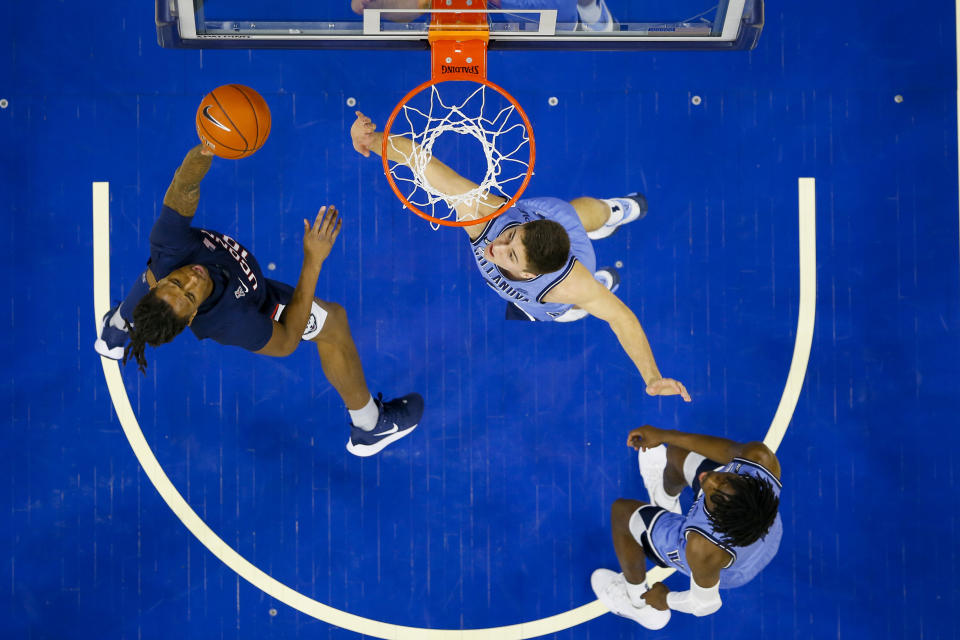 Connecticut's Brendan Adams, left, shoots the ball with Villanova's Cole Swider, center, defending during the first half of an NCAA college basketball game Saturday, Jan. 18, 2020, in Philadelphia. (AP Photo/Chris Szagola)