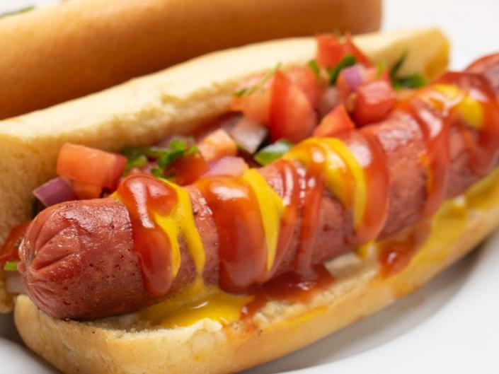 hot dog with pico de gallo salsa on white plate background