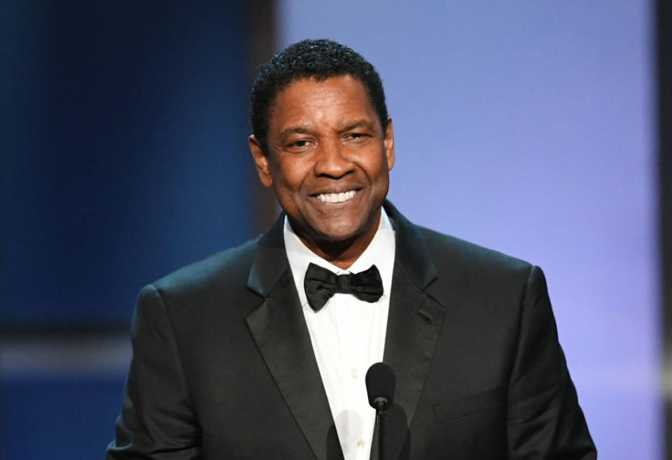 Denzel Washington smiling and standing at a podium