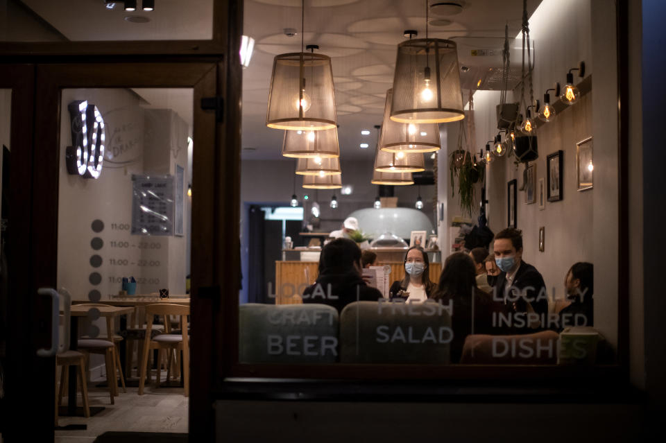 Customers wearing face masks to protect against coronavirus, sit in a restaurant in Vilnius, Lithuania, Thursday, Oct. 22, 2020. (AP Photo/Mindaugas Kulbis)