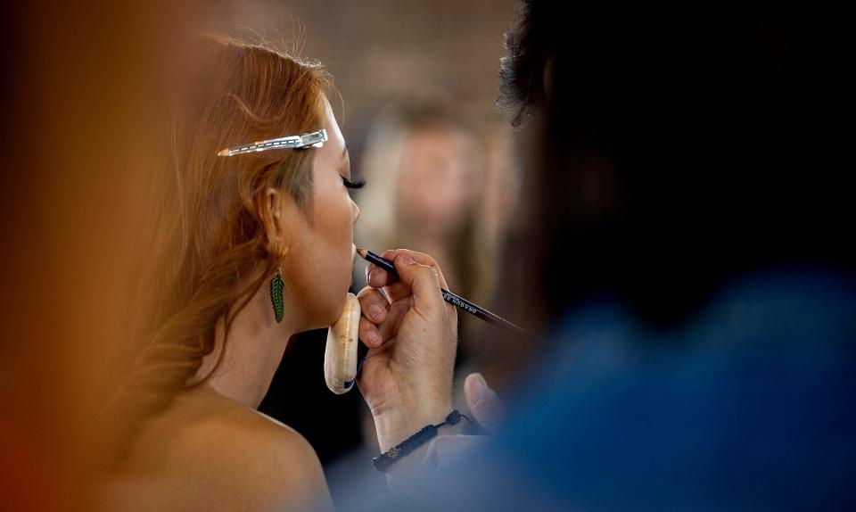Makeup artist Evan Jabbar, of the Paul Mitchell School, right, applies makeup to model Jonafina Torres, of Detroit, as they prepare to walk the runway for the Michigan Fashion Week's 10th anniversary show at Eastern Market on June 10, 2022.