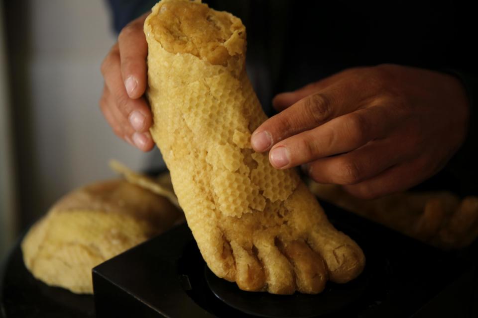 In this Tuesday March 14, 2017 photo, Palestinian artist Mohammed Abu Hashish, 28, shapes a foot in his small workshop in a refugee camp in the central Gaza Strip. The artist is crafting art out of honeycomb to draw attention to Palestinians who lost limbs in fighting with Israel. (AP Photo/Hatem Moussa)