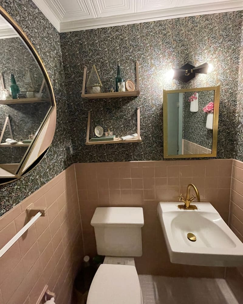 Floral wallpaper in newly renovated bathroom with pink tile wainscoting.