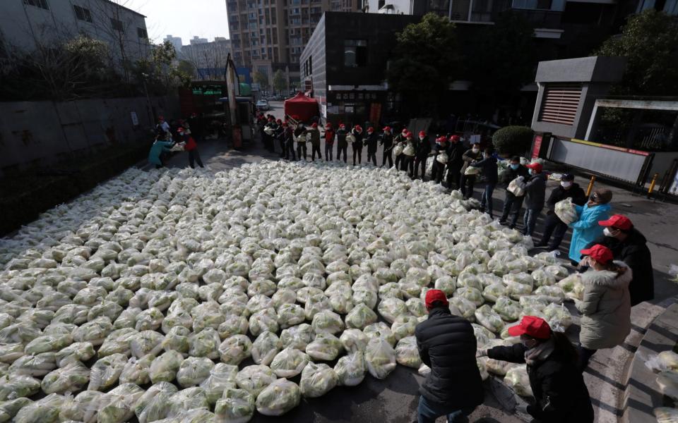 Community volunteers unload vegetables to be distributed to residents at a residential compound in Yichang city of Hubei -  CHINA DAILY / REUTERS