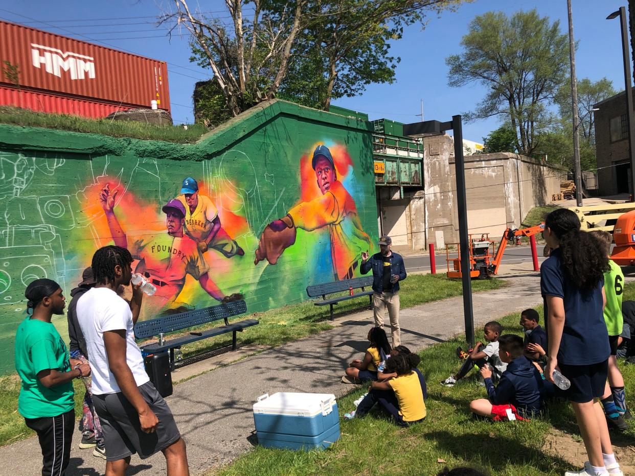 Boys and Girls Club members get an art lesson from muralist Thomas “Detour” Evans, a Colorado-based artist who painted the Foundry Giants mural at Foundry Field in Southeast Park in South Bend.