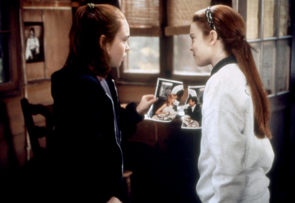 Two characters from 'The Parent Trap' film facing each other, holding a photo