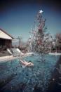 <p>Rita Aarons, the wife of iconic lifestyle photographer Slim Aarons, lounges in their California pool near her husband's Christmas tree installation. </p>
