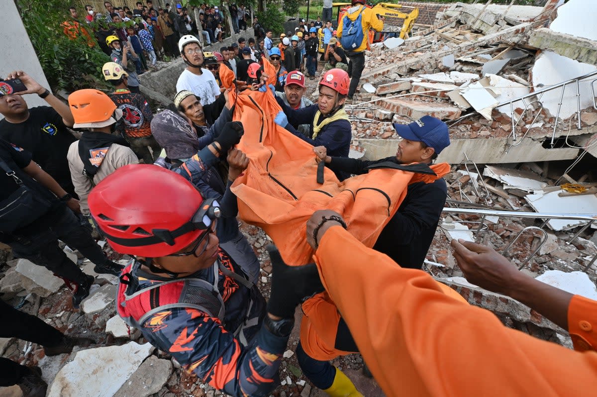 Rescue workers carry the body of a victim in Cianjur on 22 November 2022, following a 5.6-magnitude earthquake (AFP via Getty Images)