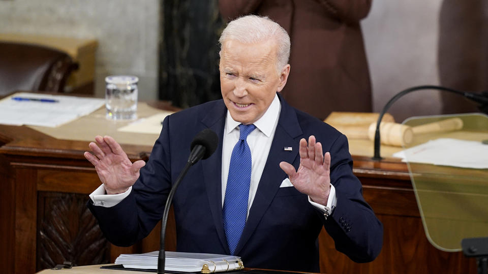 President Biden raises both hands as he delivers his State of the Union address.