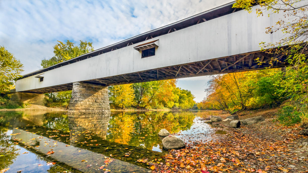 Potter's Covered Bridge crosses the West Fork of the White River surrounded by colorful fall foliage in Noblesville, Indiana.