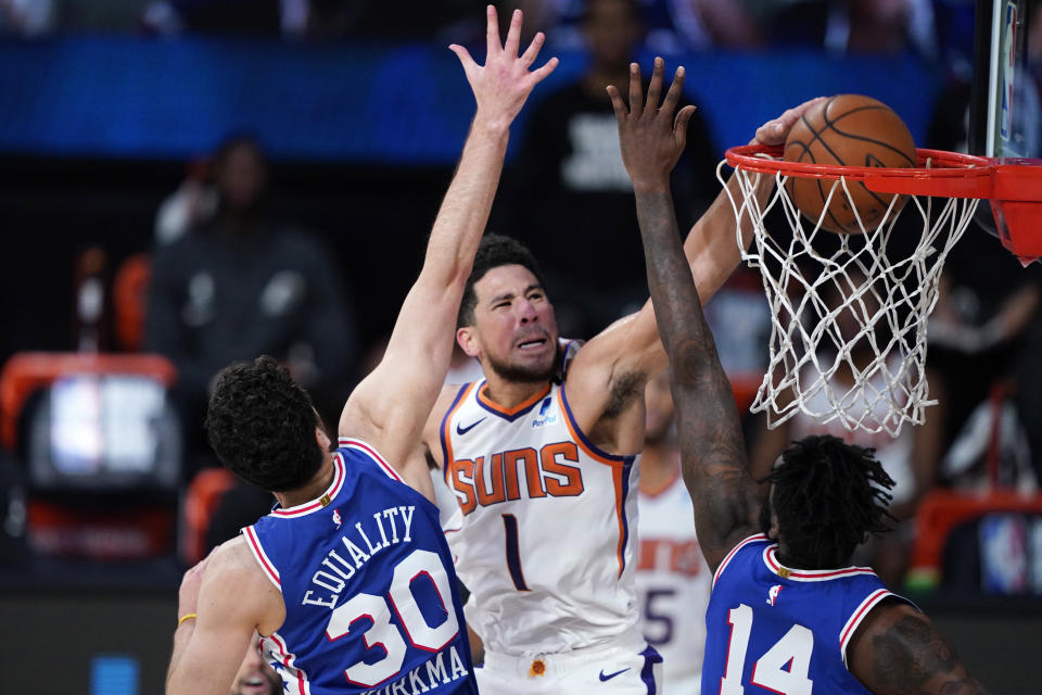 Phoenix Suns guard Devin Booker (1) makes a basket as Philadelphia 76ers guard Furkan Korkmaz (30) and forward Norvel Pelle (14) defend during the second half of an NBA basketball game Tuesday, Aug. 11, 2020, in Lake Buena Vista, Fla. (AP Photo/Ashley Landis, Pool)