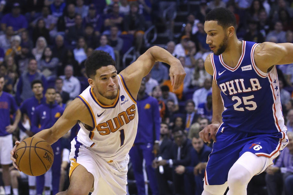 Phoenix Suns guard Devin Booker (1) drives past Philadelphia 76ers guard Ben Simmons (25) during the second half of an NBA basketball game, Monday, Nov. 4, 2019, in Phoenix. The Suns defeated the 76ers 114-109. (AP Photo/Ross D. Franklin)