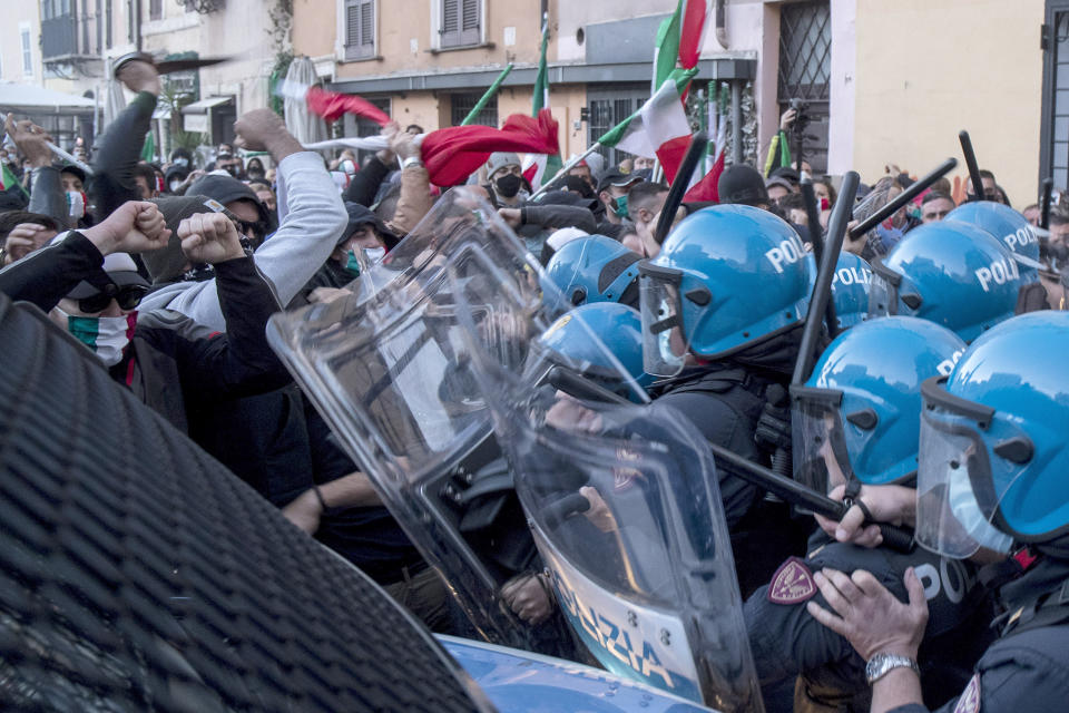 Demonstrators, some waving Italian flags, clash with police in anti-riot gear during a protest against the government's restriction measures to curb the spread of COVID-19, in Rome's Campo dei Fiori Square, Saturday, Oct. 31, 2020. (Roberto Monaldo/LaPresse via AP)